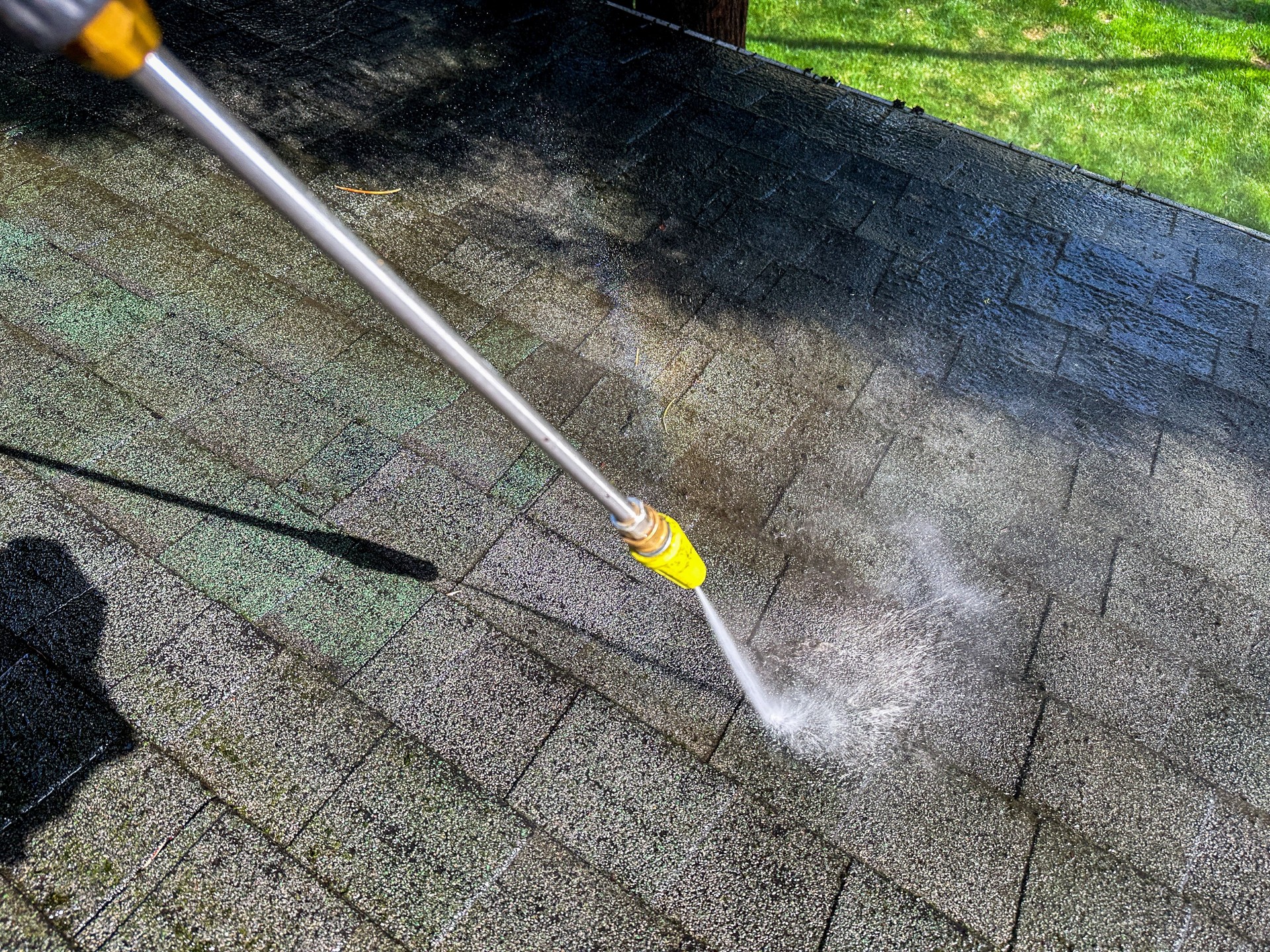 Cleaning a roof with a pressure washer on a sunny day in a backyard